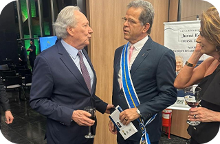 Descrição: Fotografia na qual vemos o desembargador-presidente do TRT, Valdir Florindo, conversando com o ministro da Justiça e Segurança Pública, Ricardo Lewandowski. Ambos vestem terno e Valdir Florindo também usa uma faixa.